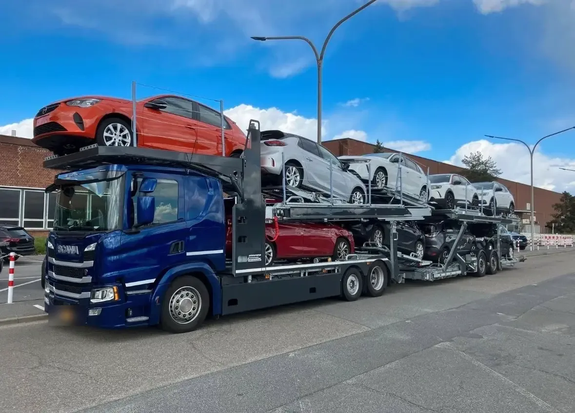 Blue Scania car transporter fully loaded with new cars at a logistics yard - brentalogistics.com